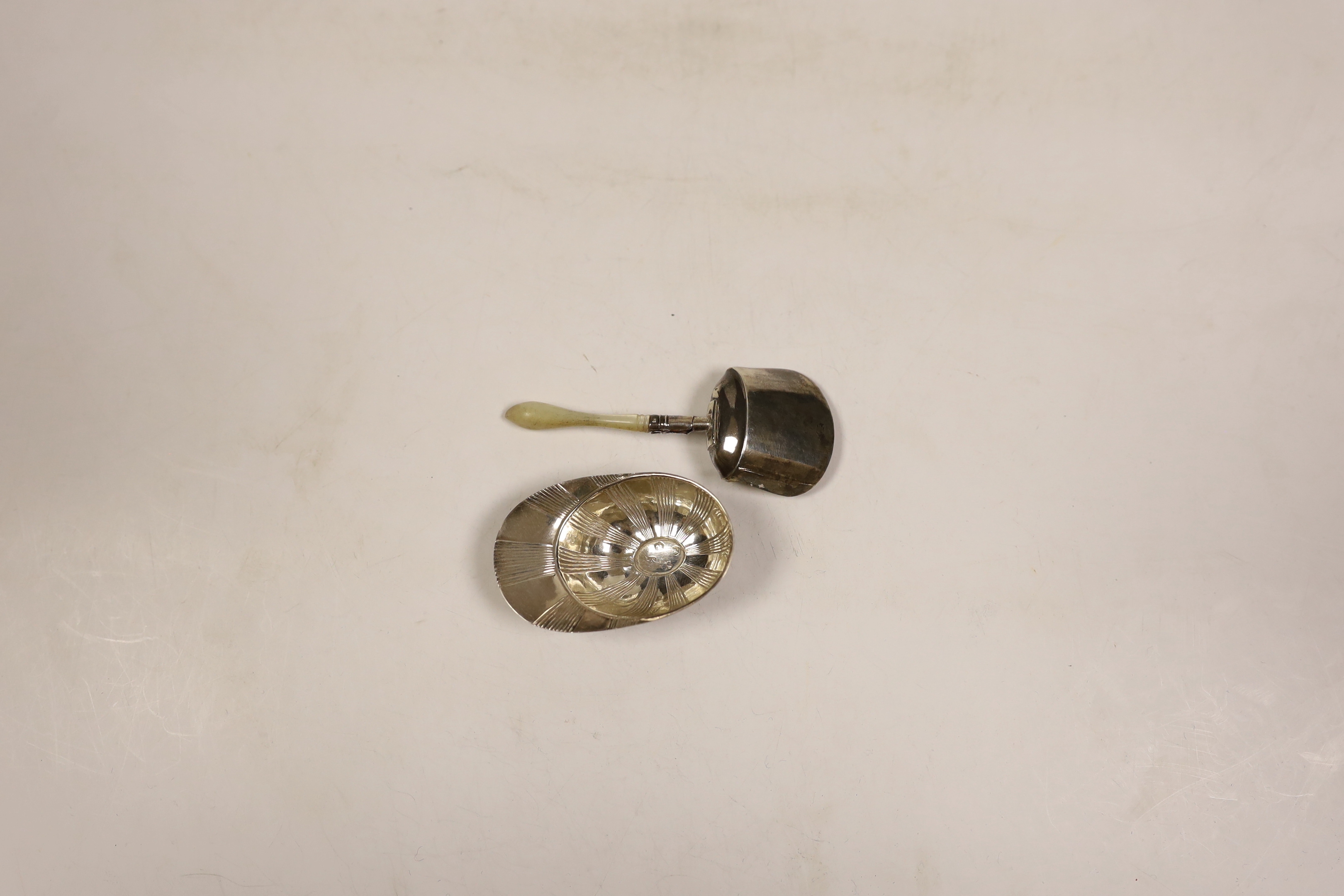 A George III silver jockey cap caddy spoon, Birmingham, 1798?, 54mm and another George III silver gilt shovel caddy spoon, with mother of pearl handle, Birmingham, 1806.